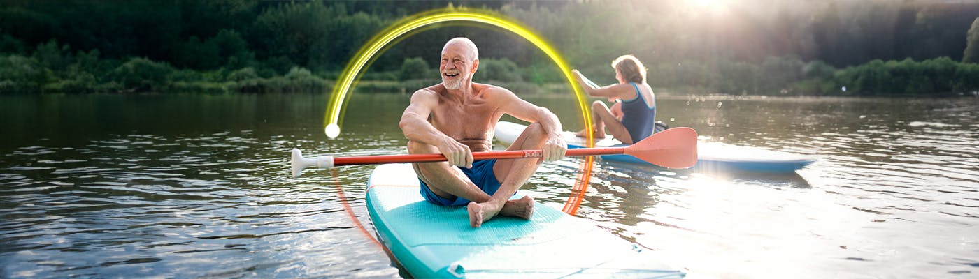 An elderly couple padelboarding with a globe of protection